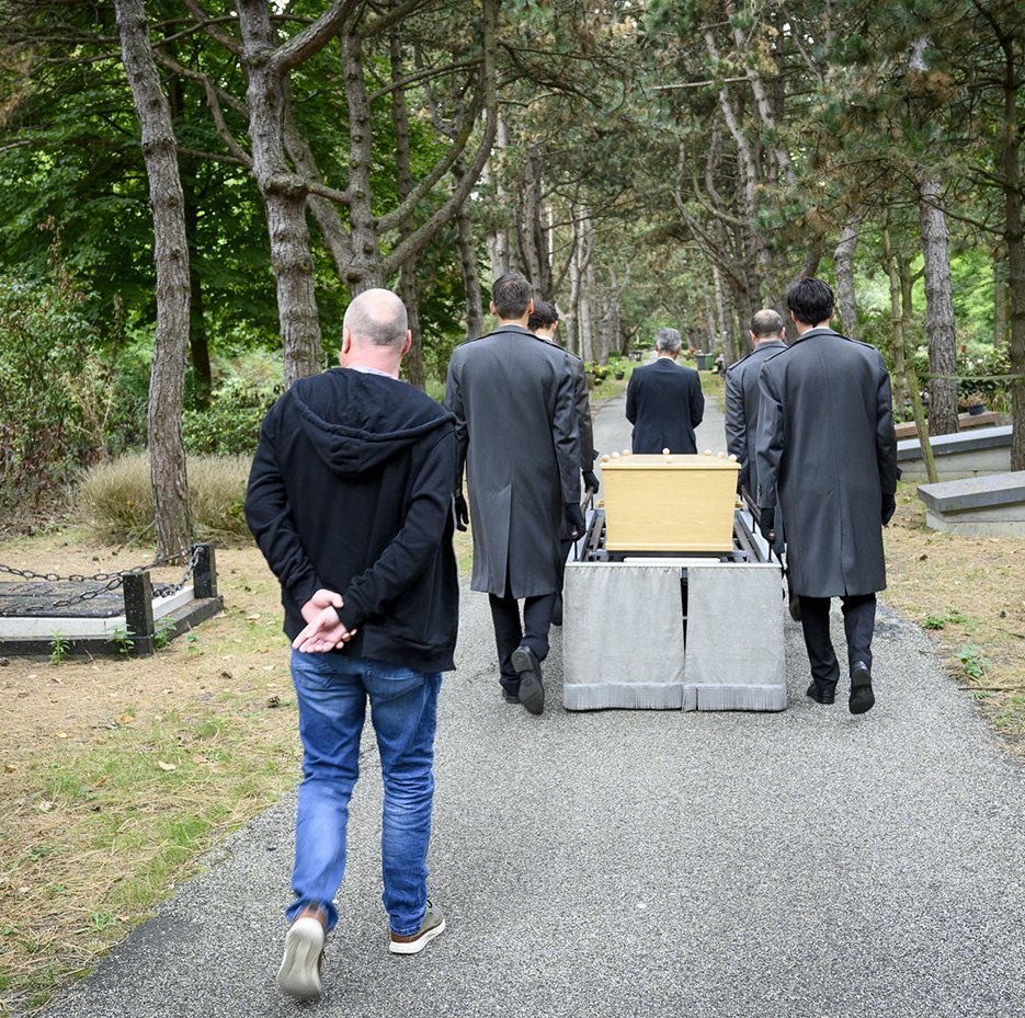 In spijkerbroek achter de kist van een eenzame uitvaart. Foto: Hein Athmer.